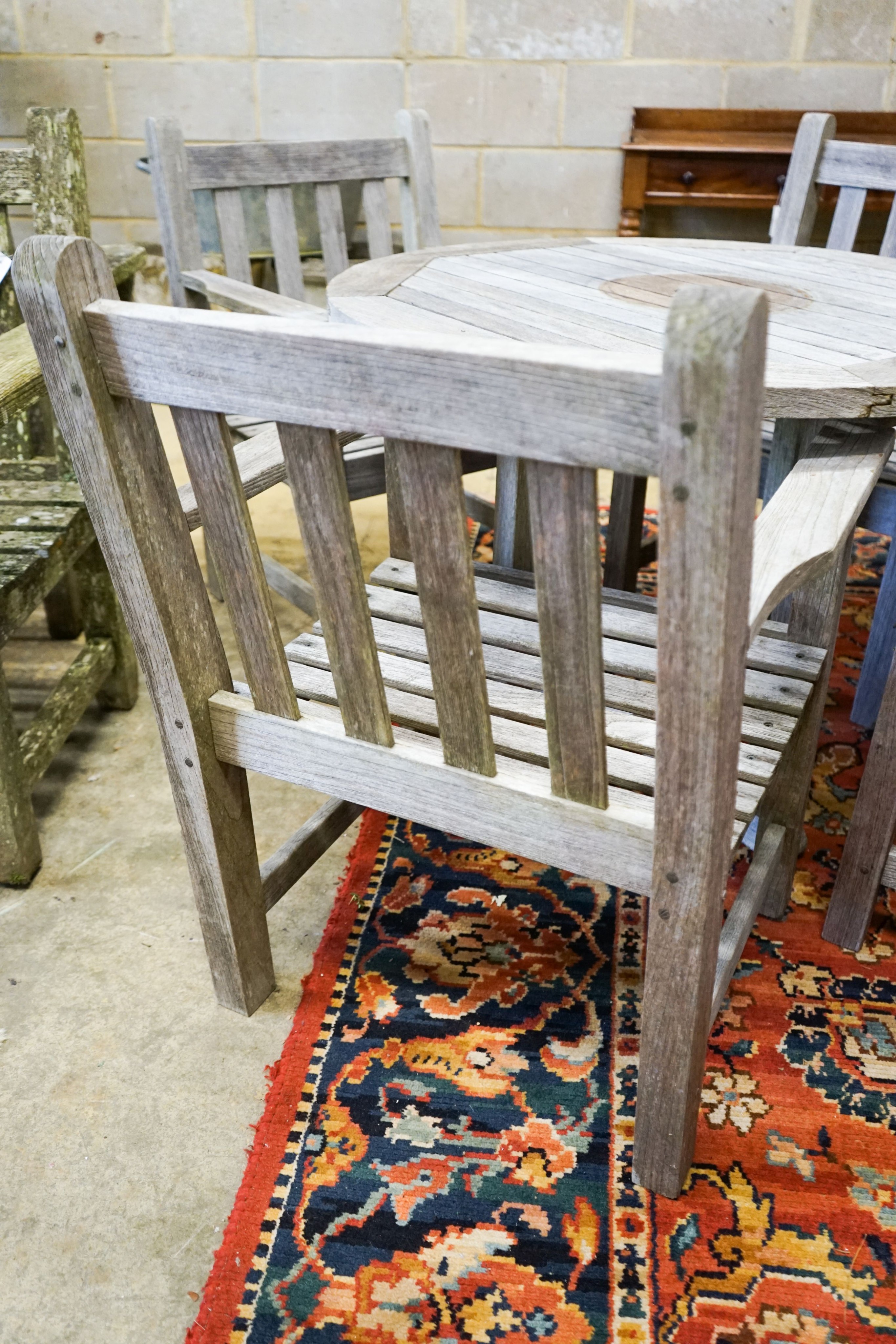 A set of four teak garden chairs and a circular parasol table, diameter 91cm chairs width 60cm